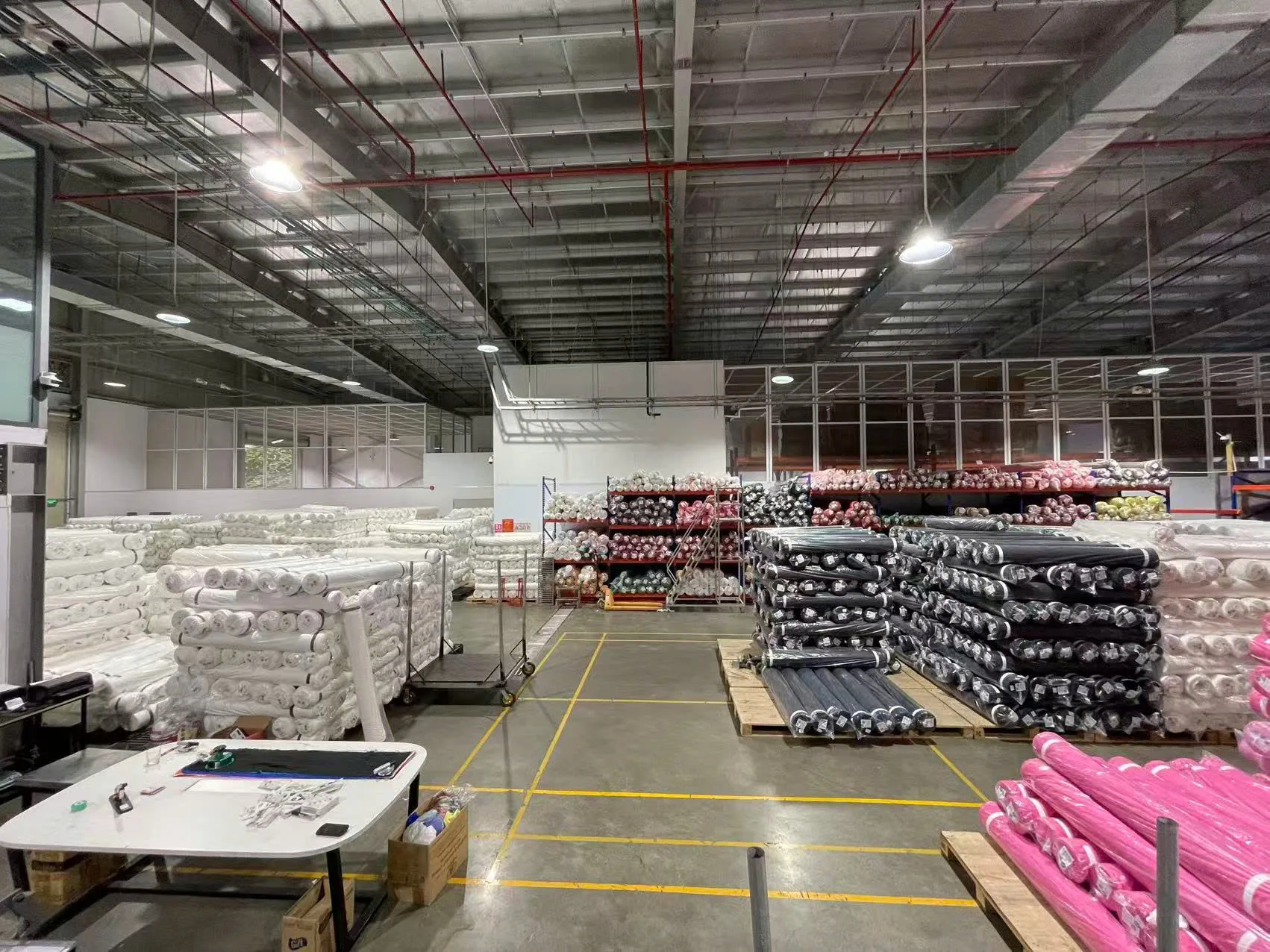 Kho vải với các cuộn xếp trên bàn kiểm