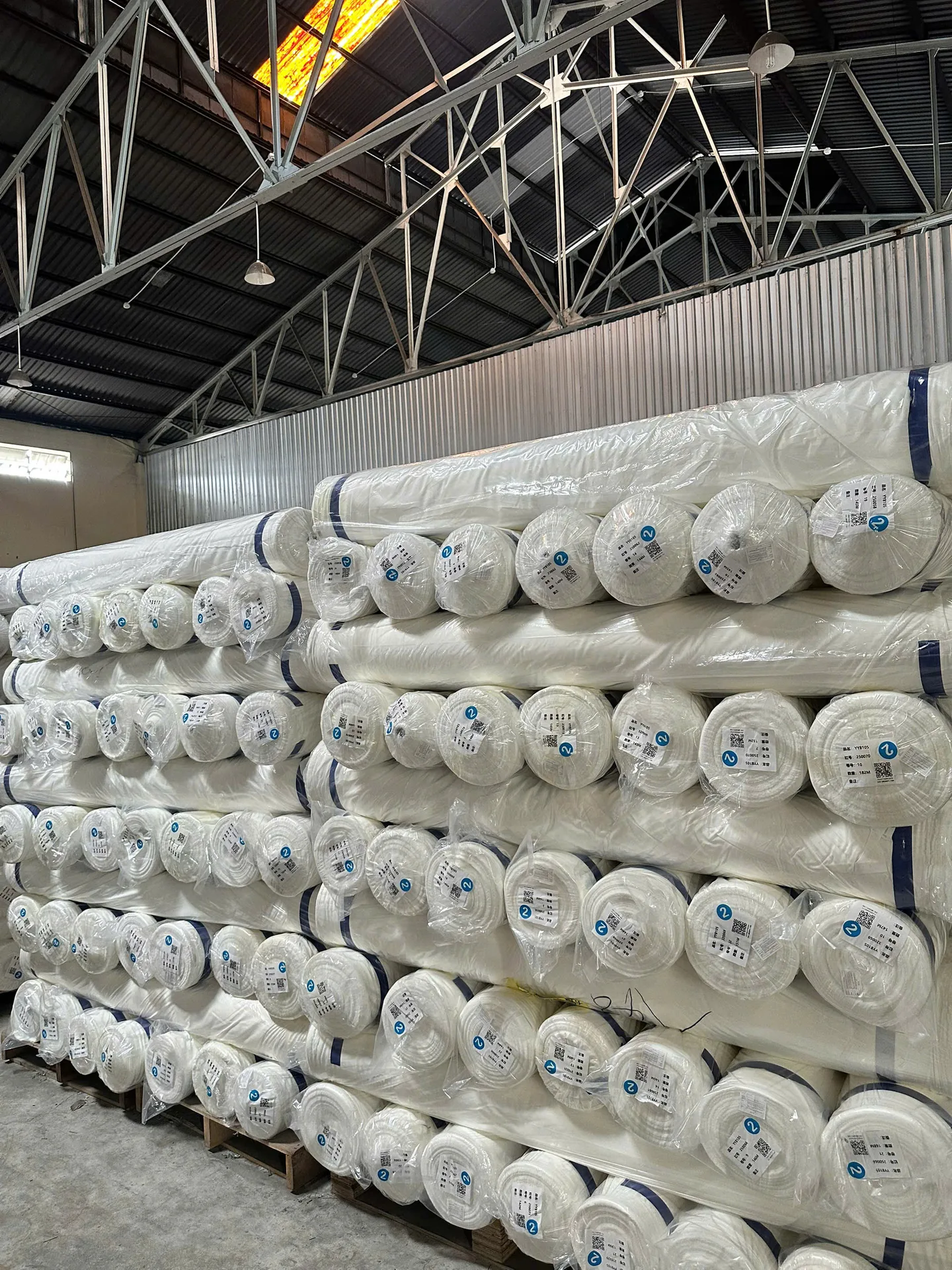 Kho cuộn vải trắng xếp cao trong nhà xưởng